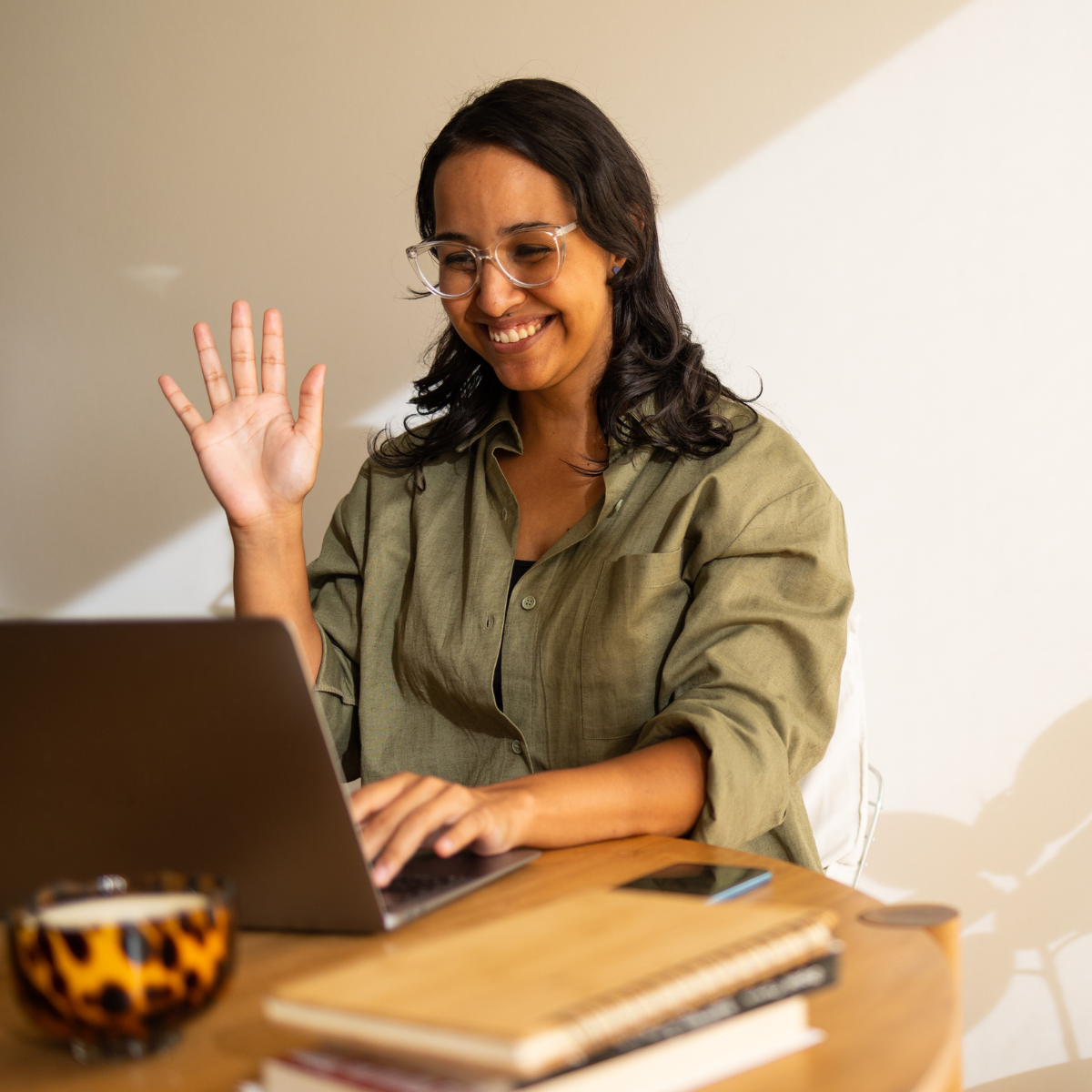 Picture of woman looking at laptop on Zoom call Woman waving and looking at Laptop on a virtual group session